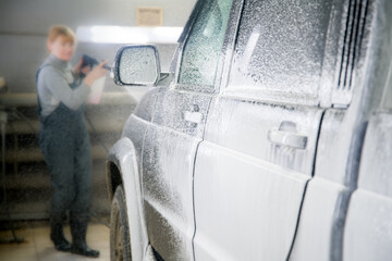 Applying a foam solution to a car at a shallow depth of field. One of the stages of car wash