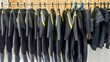A row of full length neoprene dive wetsuits hanging on a rack in a resort dive shop in the Philippines.