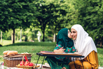 Wall Mural - Portrait of happy religious enjoy happy love asian family arabic muslim mother and little muslim girls child with hijab dress smiling and having fun moments good time in summer park