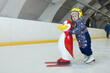 © Yekatseryna - girl 3 years old learn to skate on an indoor Ice skating rink. A plastic penguin is being pushed by skating girl for support. Fun winter activity for little children.