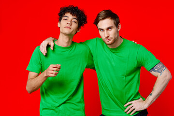 Two man green t-shirts embrace emotions friendship red background