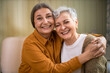 © shurkin_son - Joy, fun and happiness. Indoor shot of happy senior female in shirt hugging her short haired female friend laughing at joke, enjoying nice time together. Two middle aged best friends relaxing