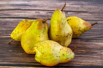 Five pears (Pyrus communis) of the Conference variety on a rustic wooden table.