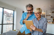 © NDABCREATIVITY - Happy smiling mature couple using digital tablet at home
