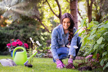 Happy Young Woman Planting Flowers In The Garden
