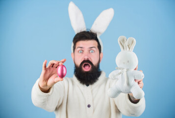 Wall Mural - Funny bunny with beard and mustache hold pink egg. Easter symbol concept. Bearded man wear bunny ears. Egg hunt. Look what i found. Hipster cute bunny blue background. Easter bunny. My precious