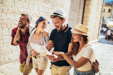 group of tourists searching for places on their map outdoors.