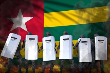 Togo protest stopping concept, police squad in heavy smoke and fire protecting country against disorder - military 3D Illustration on flag background