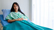 © Bangkok Click Studio - Young Asian lady patient lay down on blue bed green blanket white room in hospital. Look at camera seems still unwell but will recover soon as already in good hands.