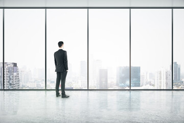 Wall Mural - Vision concept with businessman looking through big window on city skyscrapers in empty office hall with glossy floor.