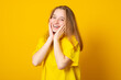 Studio portrait of a smiling teenage girl on a yellow background.