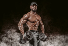 Muscular Athlete Posing In The Studio With Dumbbells. Fitness And Classic Bodybuilding Concept.