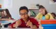 © TommyStockProject - Portrait of preteen african kid in headphones rapping sitting at desk in classroom