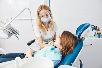 Wall Mural - Orthodontist drilling boy side teeth with handpiece