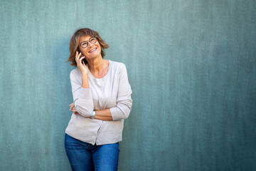 Wall Mural - older woman talking with mobile phone by green background