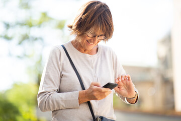 Sticker - smiling older woman using mobile phone outdoors