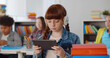 © TommyStockProject - Portrait of cute redhead preteen girl in headphones using digital tablet at classroom