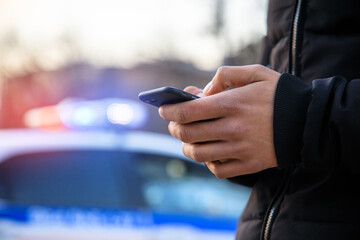 man holding phone with police in street