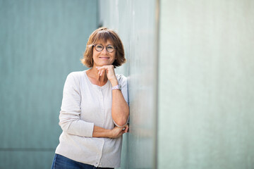 Wall Mural - older woman leaning against wall and smiling
