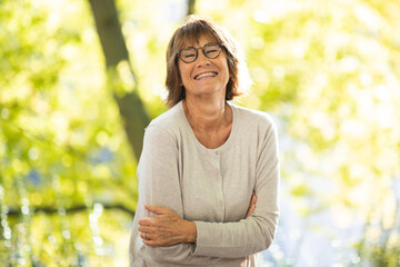 happy older woman standing in park