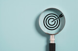 Target board inside of magnifier glass for focus business objective on blue background and copy space.