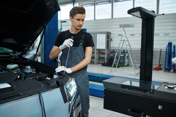 Wall Mural - Male worker adjusts the headlights, car service