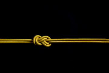 Eight knot with yellow rope on black background.