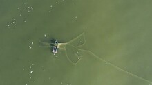 AERIAL: Fishermans Casting Nets In The Green Baltic Sea With Gulls Flying Around Searching For A Fish