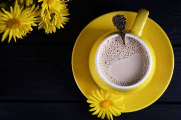 Yellow ceramic cup with latte art coffee on a dark background. View from above