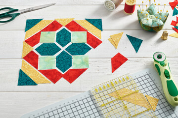 Wall Mural - Pieces of fabric laid out in the shape of a patchwork block, sewing and quilting accessories.