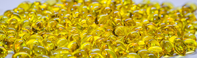 Fish oil capsules with omega 3 and vitamin D, isolated on white background. Yellow vitamin pills. Medicine and healthy.