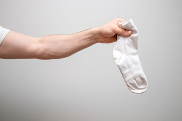 Canvas Print - Closeup shot of a male holding a white sock on a plain background