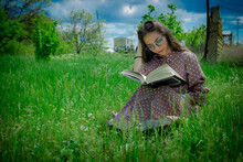 A Pretty Woman Sitting On The Grass, Girl Reading A Book In The Park, Woman Reading A Book