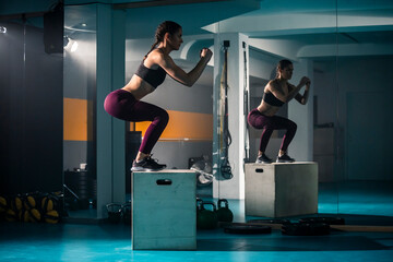 A young female doing a box jump in the gym