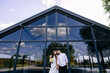 © Ivan - Newlyweds stand against the background of large windows. The bride is holding a beautiful bouquet in her hands