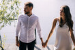 © Ivan - Newlyweds at the pier. The bride and groom walk along the pier to hold hands, in fashionable clothes near a green tree, pensive look to the side.
