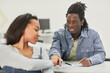 © Seventyfour - Portrait of two African-American students passing notes during class in school, copy space
