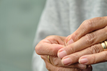 Close-up of female hands trying to thread a needle with sewing thread. Selective focus,