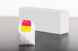 Single tea bag in front of a blurred pack on a gray table