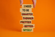 Be myself symbol. Businessman hand. Wooden blocks with words 'i need to be myself, not smarter, thinner, prettier, better'. Beautiful orange background, copy space. Psychological, be myself concept.