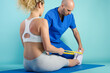 © alphaspirit - Girl performs exercises with a physiotherapist. Cyan background