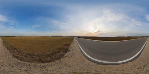 Country asphalt road among fields at sunset or sunrise with beautiful sky and cirrus clouds, spherical panorama 360 degrees. VR content.