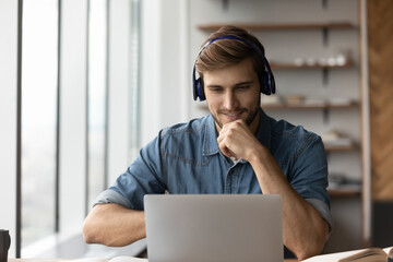 smiling young male student in headphones watch webinar on computer study online from home. happy man