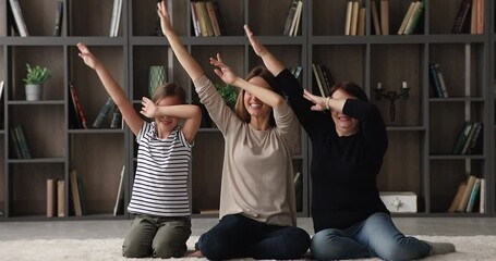 Wall Mural - Happy three generations family 60s granny little girl her young mom sit on floor in modern living room make dab popular youth culture gesture have fun together at home, perform triumph dance concept