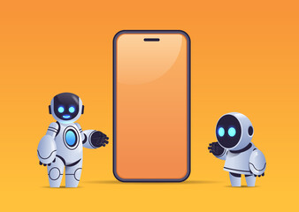 Poster - two robots standing near smartphone with blank screen robotic character artificial intelligence technology concept