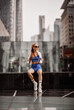 © Dmitry Lobanov - Athlete slim blonde fitness woman trainer runner in blue sportswear, towel around neck is sitting taking rest after workout exercise, jog on form on city street in business downtown center in Dubai