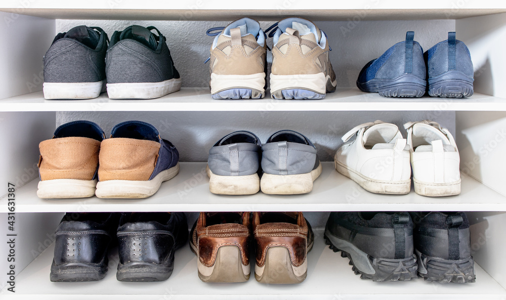 Many shoes of man and woman in different fashion style put in 3 storeys white shoe rack. Everyday footwear collection use for variety seasons and lifestyle (sport, casual and leather business shoes). - obrazy, fototapety, plakaty 