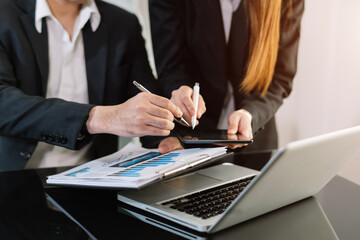 Business documents on office desk with tablet, graph and two colleagues discussing data working .