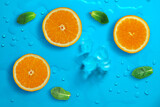 Fototapeta Kuchnia - Fresh juicy slices of orange and mint leaves on bright blue background covered with water drops. Creative food background, top view