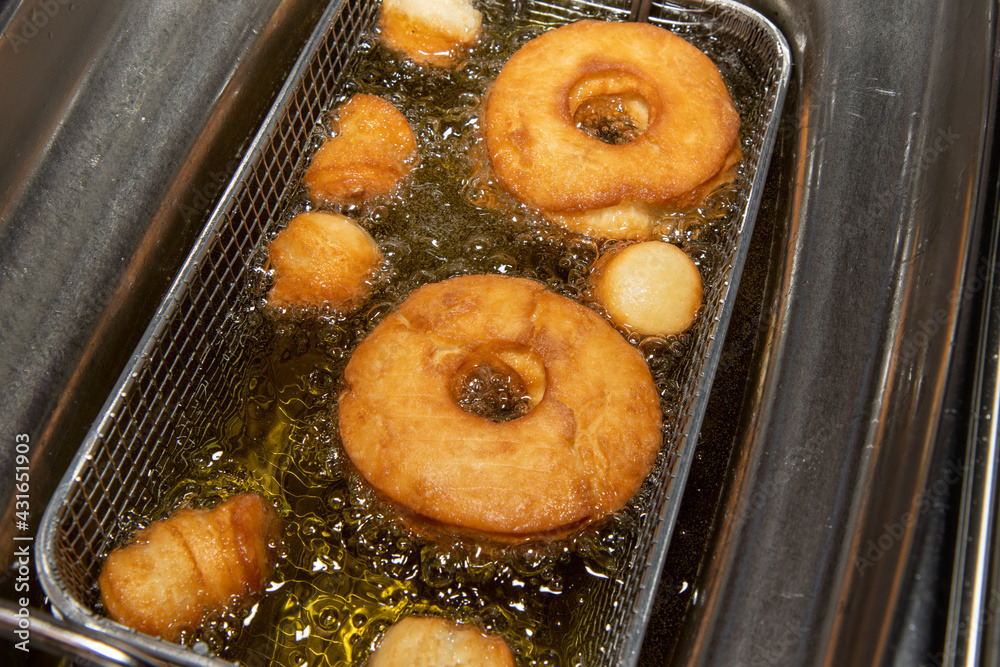 Delicious doughnuts and doughnut holes being cooked in a oil fryer